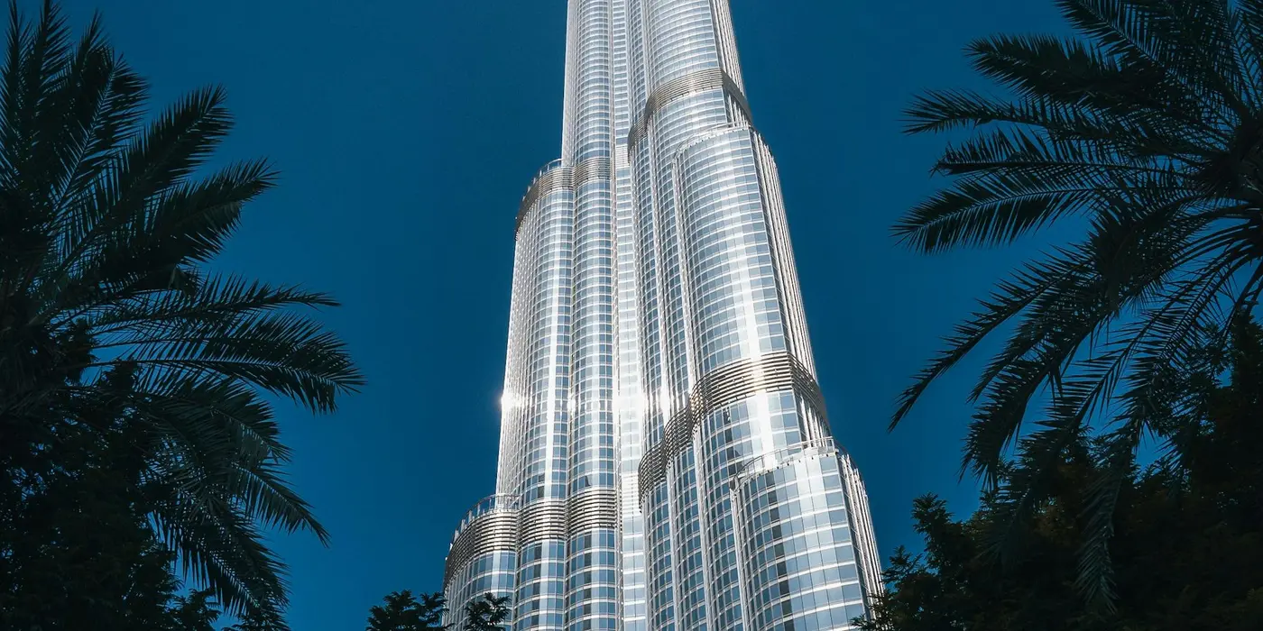 Burj Khalifa rising above palm trees against a deep blue evening sky